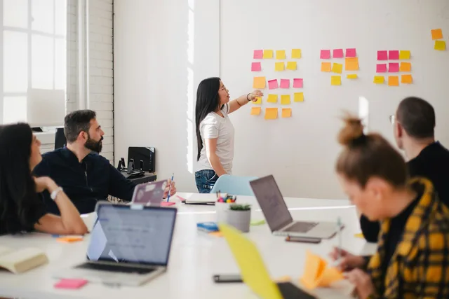 People gathered around a desk with sticky notes on a board